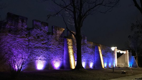 Violett beleuchtete Steinermauer bei Nacht