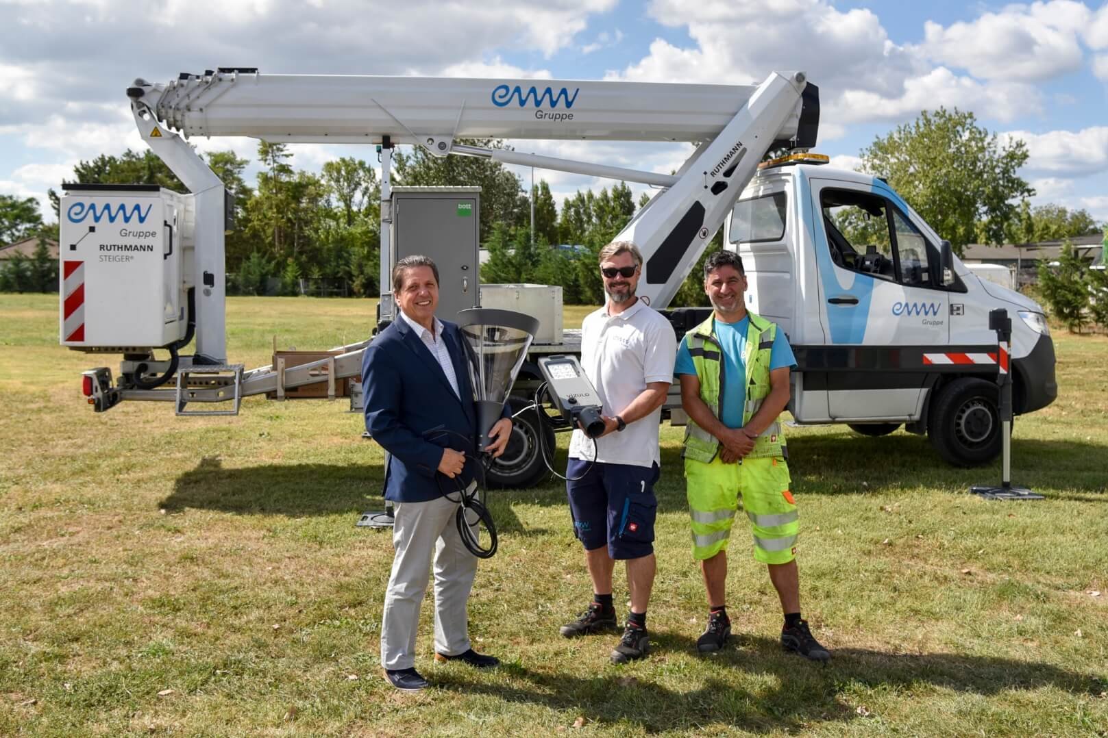 Bürgermeister von Leopoldsdorf, Fritz Blasnek, steht mit zwei Monteuren der eww Anlagentechnik vor einem Hubsteiger