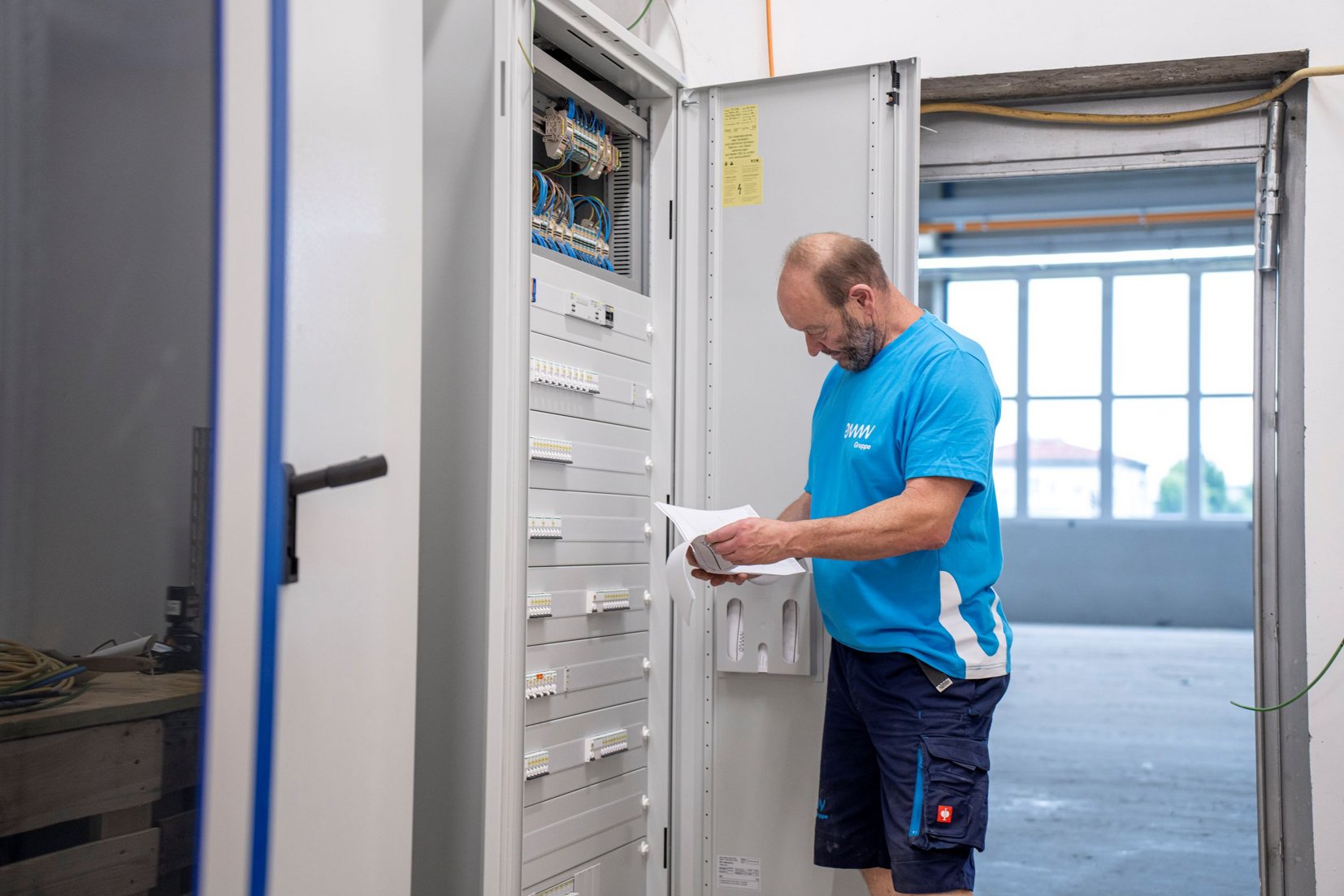 Projekt Mettec Elektriker vor Schaltkasten Projekt Mettec Elektriker vor Schaltkasten