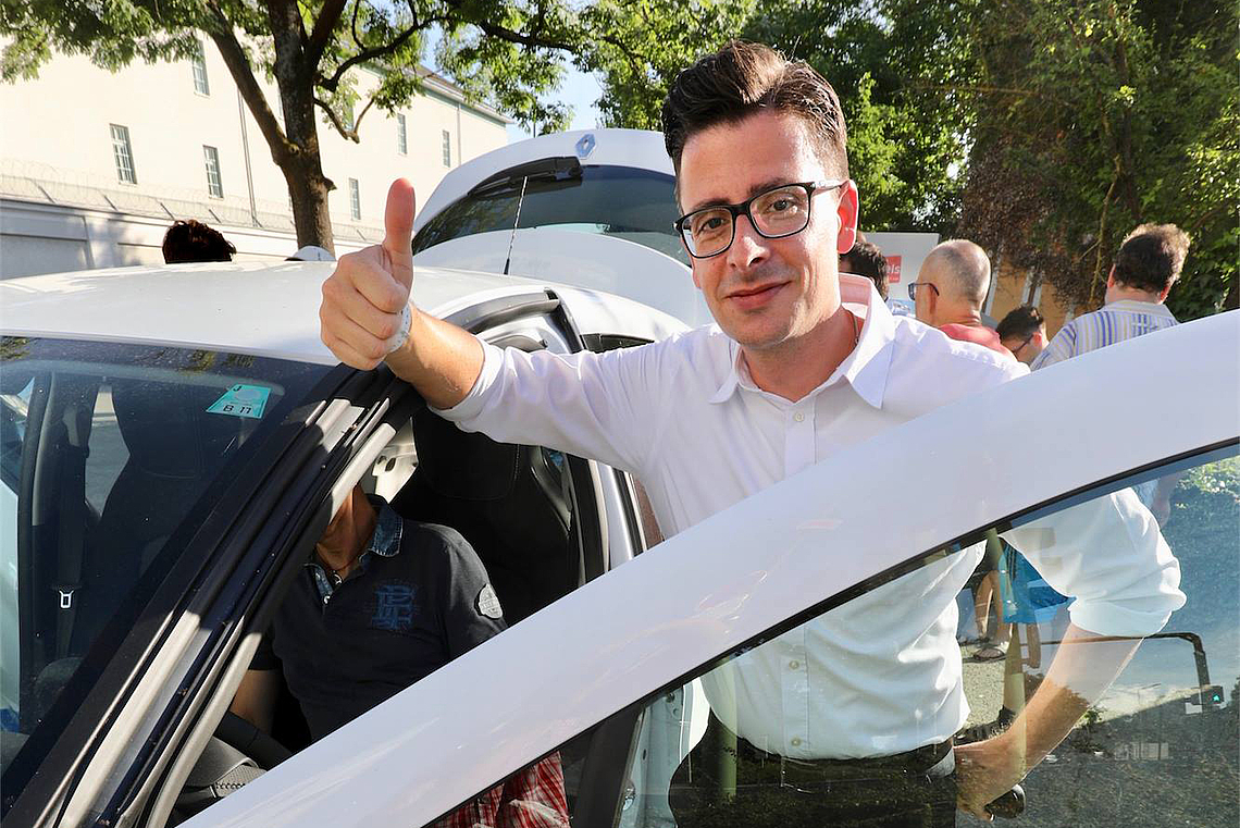 Wolfgang Vallant lehnt am Auto und zeigt mit dem Daumen nach oben